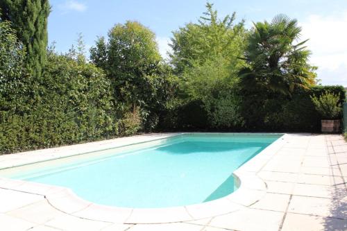 een zwembad in een tuin met bomen bij Petit gite in Cours-de-Pile