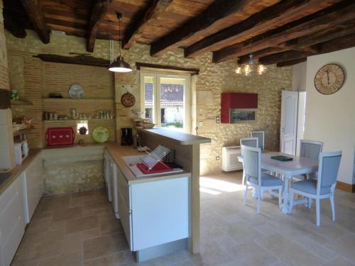 une cuisine avec un comptoir, une table et des chaises dans l'établissement Chez la marie, à Saint-Pierre-de-Chignac