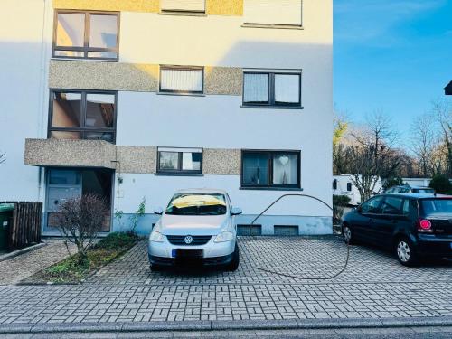 two cars parked in a parking lot in front of a building at Apartment Messe Karlsruhe in Rheinstetten