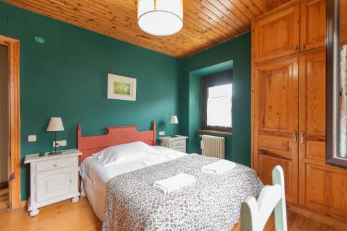 a bedroom with a bed and a green wall at Petit Verneda in Casau