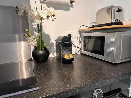 - une cuisine avec un four micro-ondes et des fleurs sur un comptoir dans l'établissement AJ - Stylish Pied-à-Terre à La Joliette - Parking, à Marseille