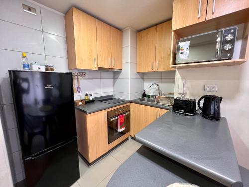 a kitchen with a black refrigerator and wooden cabinets at Hermoso departamento en parque urbano 1 in Concepción