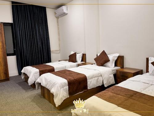 a hotel room with three beds in a room at Motel Taj in As Sulaymānīyah