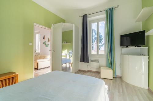 une chambre avec un lit blanc et une télévision dans l'établissement Le Lamartine - Appt climatisé proche du port, à La Ciotat