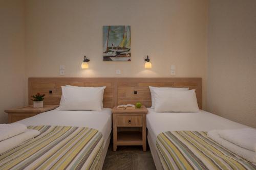 a room with two beds and a nightstand between them at Agnanti Hotel Apartments in Afissos