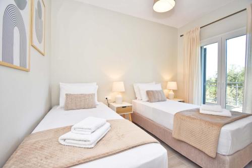 two beds in a white room with a window at Villa Caesar in Agios Ioannis