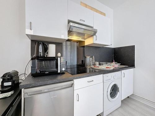 una cucina con mobili bianchi, lavatrice e asciugatrice di Hyper-centre apartment Treille 29 a Clermont-Ferrand