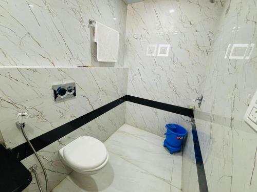 a bathroom with a toilet and a blue trash can at Hotel Delight Zone in Jodhpur