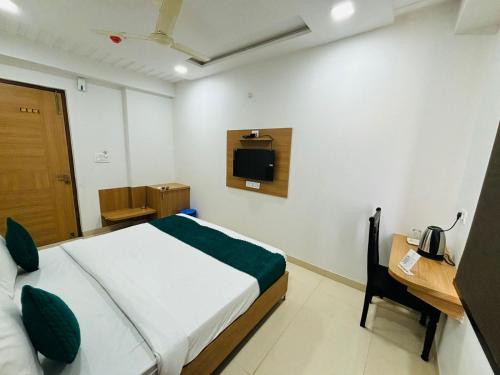 a bedroom with a bed and a desk and a television at Hotel Delight Zone in Jodhpur