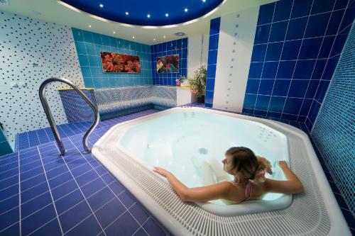 a woman sitting in a bath tub in a bathroom at Hotel Central in Plzeň