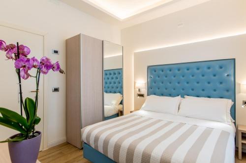 a bedroom with a bed and a vase with purple flowers at Hotel Italia Boutique in Rimini
