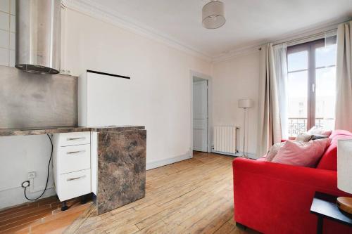 un salon avec un canapé rouge et une cuisine dans l'établissement Tour Eiffel - Saint Dominique - Invalides, à Paris