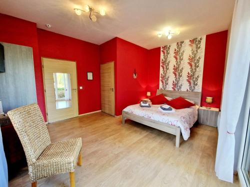 a bedroom with red walls and a bed and a chair at LES JARDINS DE LA GRANGE in Rezonville