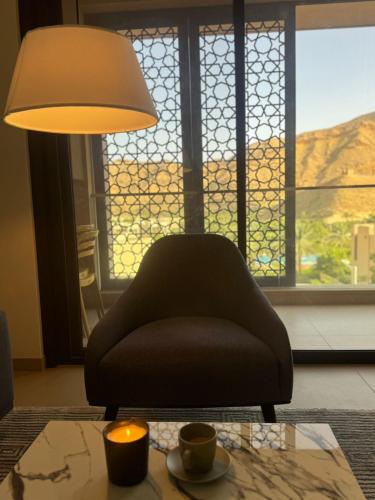 a living room with a chair and a table with a lamp at Muscat bay Zaha two bedroom apartment in Bandar Jişşah