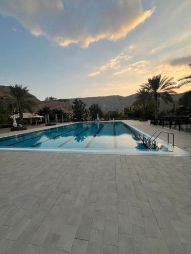 a large swimming pool with a sunset in the background at Muscat bay Zaha two bedroom apartment in Bandar Jişşah