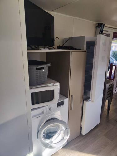 - une buanderie avec un lave-linge et une télévision dans l'établissement Joli Mobil home N137, 4ch tout confort et spacieux, à Gastes