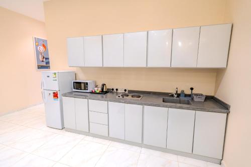 a kitchen with white cabinets and a white refrigerator at شقة خاصة مؤثثة بالكامل للتأجير اليومي in Hafr Al Baten