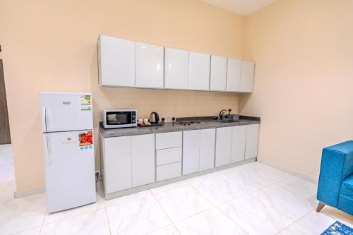 a kitchen with white cabinets and a white refrigerator at شقة خاصة مؤثثة بالكامل للتأجير اليومي in Hafr Al Baten