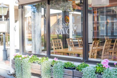 a restaurant with potted plants in front of a window at Hotel Savoy in Mariehamn