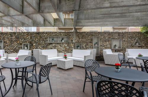 a patio with tables and chairs and couches at iH Hotels Milano Eur - Trezzano sul Naviglio in Trezzano sul Naviglio