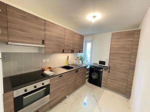 La cuisine est équipée de placards en bois, d'un évier et d'un lave-vaisselle. dans l'établissement Bel appartement pour 6 avec parking - Rive gauche - 183, à Rouen