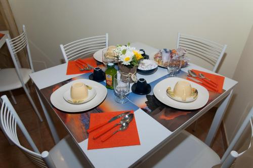 a dining room table with plates and glasses and flowers at B&B L'Orizzonte in Civitavecchia