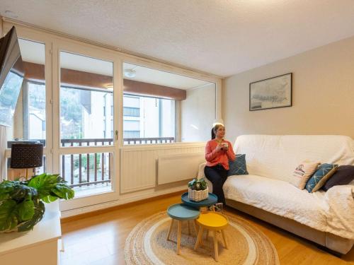 eine Frau, die auf einer Couch in einem Wohnzimmer sitzt in der Unterkunft Appartement 4 pers. proche centre ville & téléphérique - FR-1-296-473 in Saint-Lary-Soulan