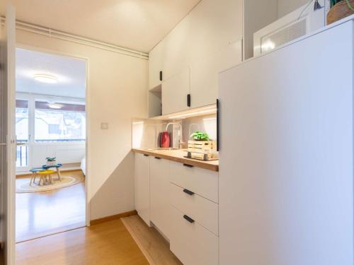 une cuisine avec des placards blancs et un couloir avec une table dans l'établissement Appartement 4 personnes, balcon, Saint Lary Village, proche commerces et téléphérique - FR-1-296-473, à Saint-Lary-Soulan