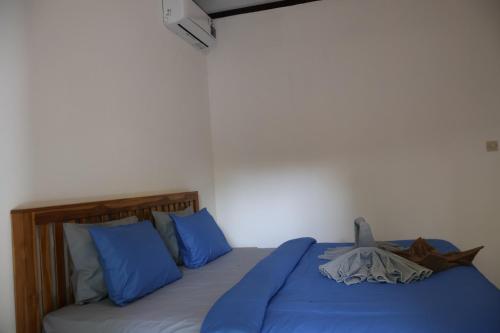 a bedroom with a bed with blue sheets and blue pillows at Rumah Tiga Gili in Gili Air