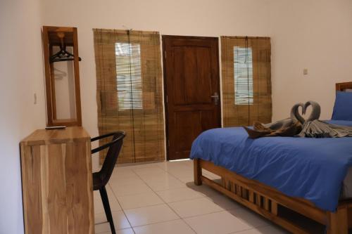 a bedroom with a bed and a mirror and a chair at Rumah Tiga Gili in Gili Air