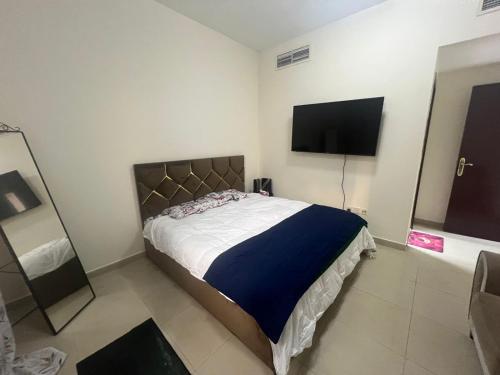 a bedroom with a bed and a flat screen tv at SHJ DXB Sunny Border Guesthouse in Dubai