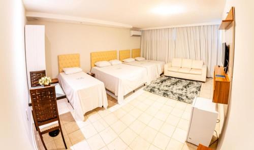 a hotel room with two beds and a television at Hotel Veneza in Itabuna