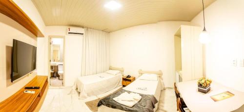 a living room with two beds and a flat screen tv at Hotel Veneza in Itabuna
