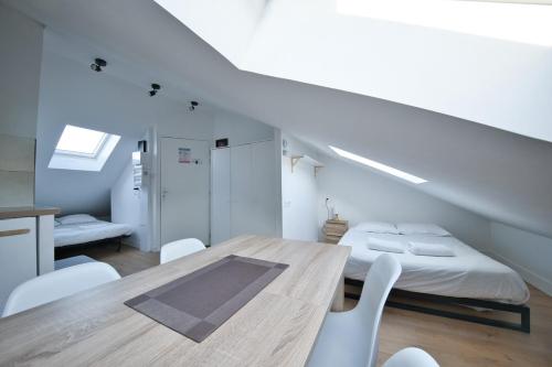 Cette chambre blanche dispose d'une table et d'un lit. dans l'établissement Rare Perle - Studio, à Reims