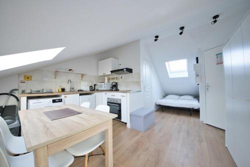 une cuisine avec une table en bois et des armoires blanches dans l'établissement Rare Perle - Studio, à Reims