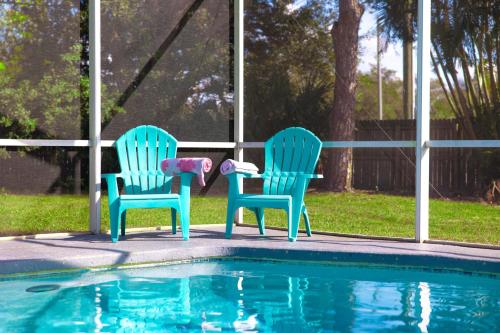 two chairs sitting next to a swimming pool at Beach Villa Private pool fire pit 6mi to beach in Pinellas Park