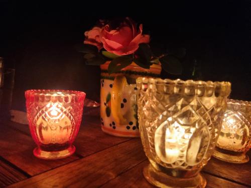 a table with three glasses and a vase with a flower at La Maison des Roses, mit Pool in Molas
