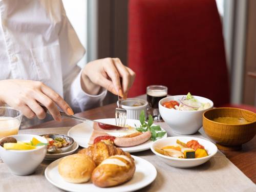a person cutting food on a table with plates of food at Mitsui Garden Hotel Sapporo in Sapporo