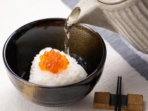 a bowl of rice with a person pouring rice into it at Mitsui Garden Hotel Sapporo in Sapporo