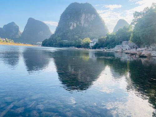 a river with mountains in the background with water at Dyed Mount Boutique Hotel in Yangshuo