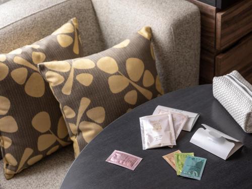 a table with pillows next to a couch with a table sidx sidx at Mitsui Garden Hotel Sapporo in Sapporo