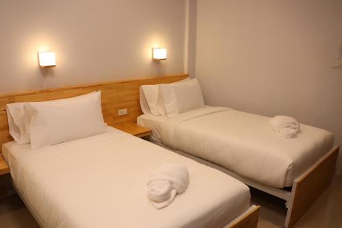 two beds in a room with white sheets and towels at Moya Boutique Hotel in Betong