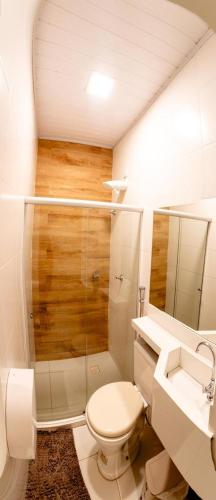 a white bathroom with a toilet and a sink at Hotel Veneza in Itabuna