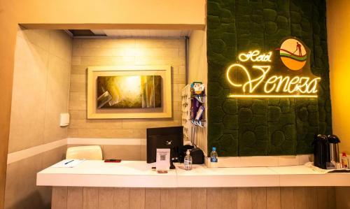 a counter in a restaurant with a sign on the wall at Hotel Veneza in Itabuna