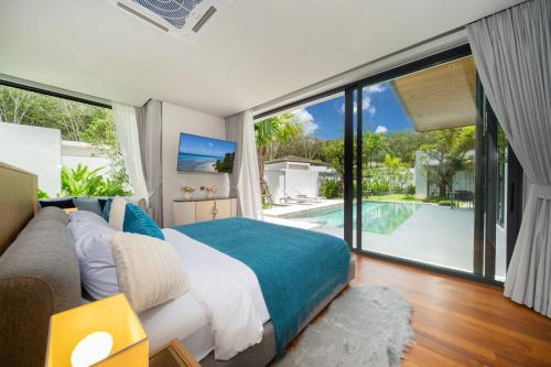 une chambre avec un lit et une vue sur une piscine dans l'établissement Bang Tao Botanica Modern Loft 3 bd, à Ban Pak Lak