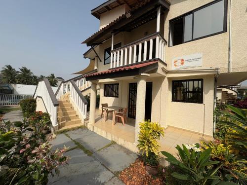 a house with a porch and a table in front of it at Appartement confortable à Grand Popo, 50 m², piscine partagée in Grand-Popo