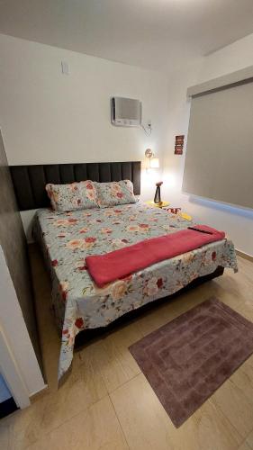 a bedroom with a large bed with a red blanket at Studio Nosso Sonho in Cabo Frio