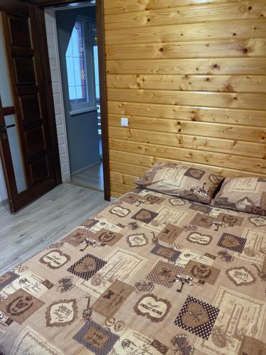 a bed in a bedroom with a wooden wall at Nice House in Slavske