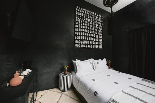 a bedroom with a white bed and a black wall at Riad Dar Bousga in Marrakech
