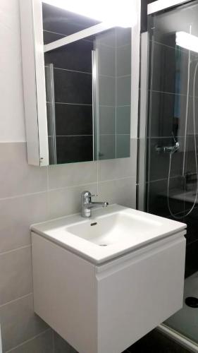 a white bathroom with a sink and a shower at Ferienwohnung am Bielersee in Erlach
